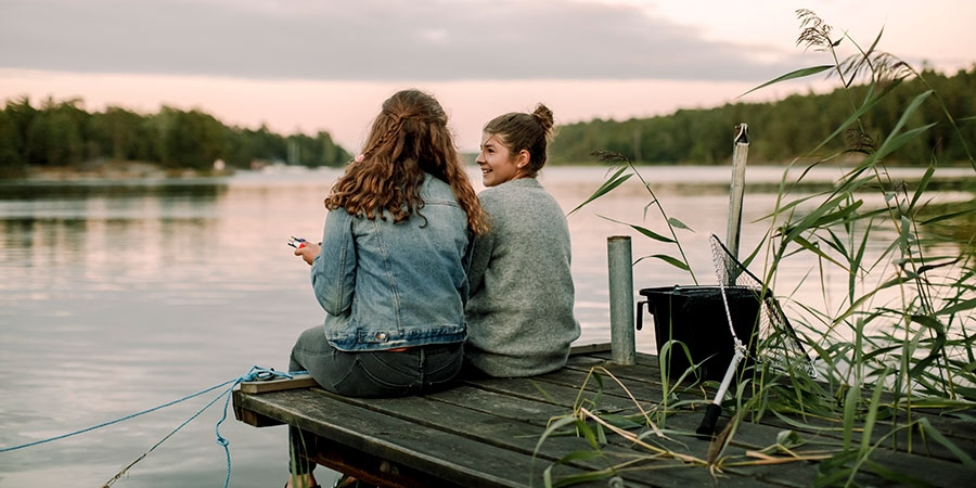 Två flickor på brygga vid sjö